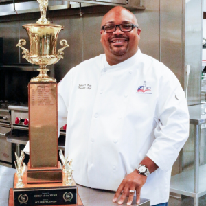 Chef James in a white coat holding an award 